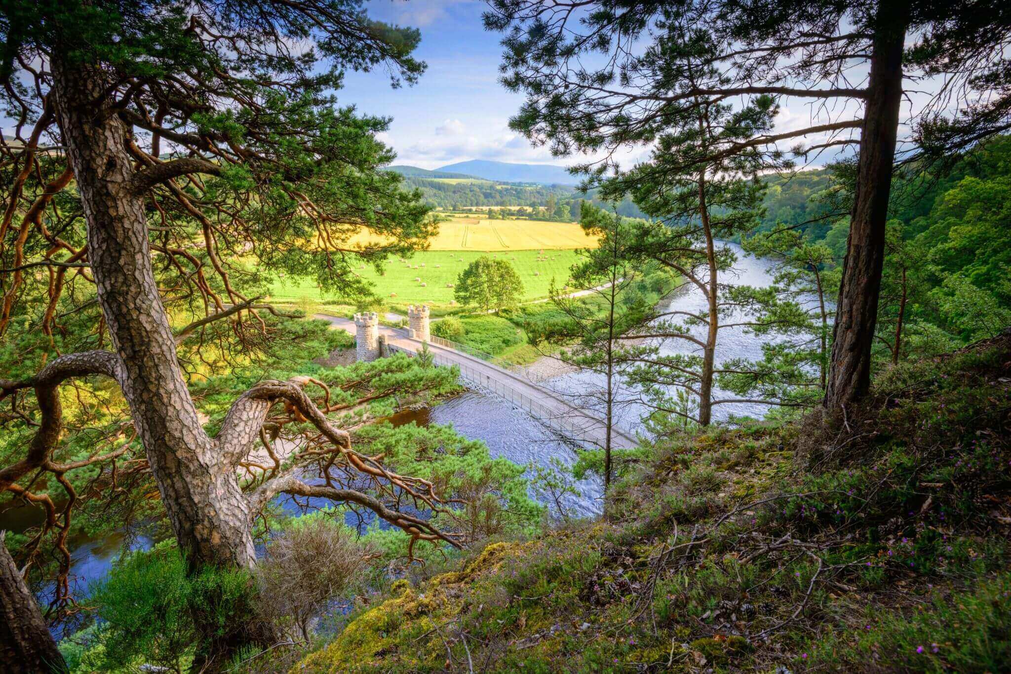 View of a stone bridge crossing a river in a rural landscape.