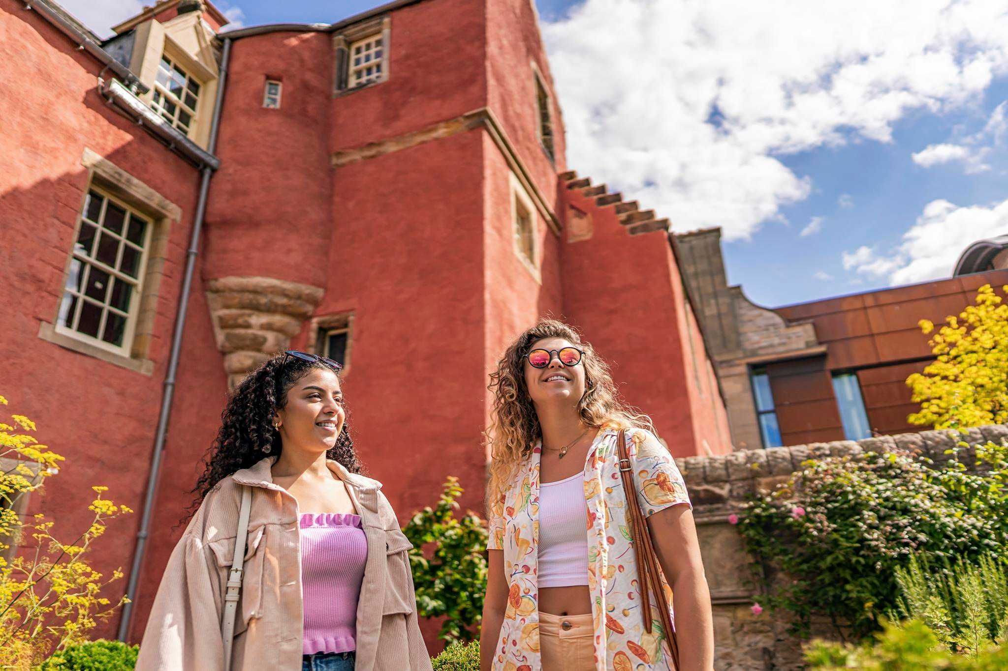 Two visitors to Abbot House standing the gardens smiling