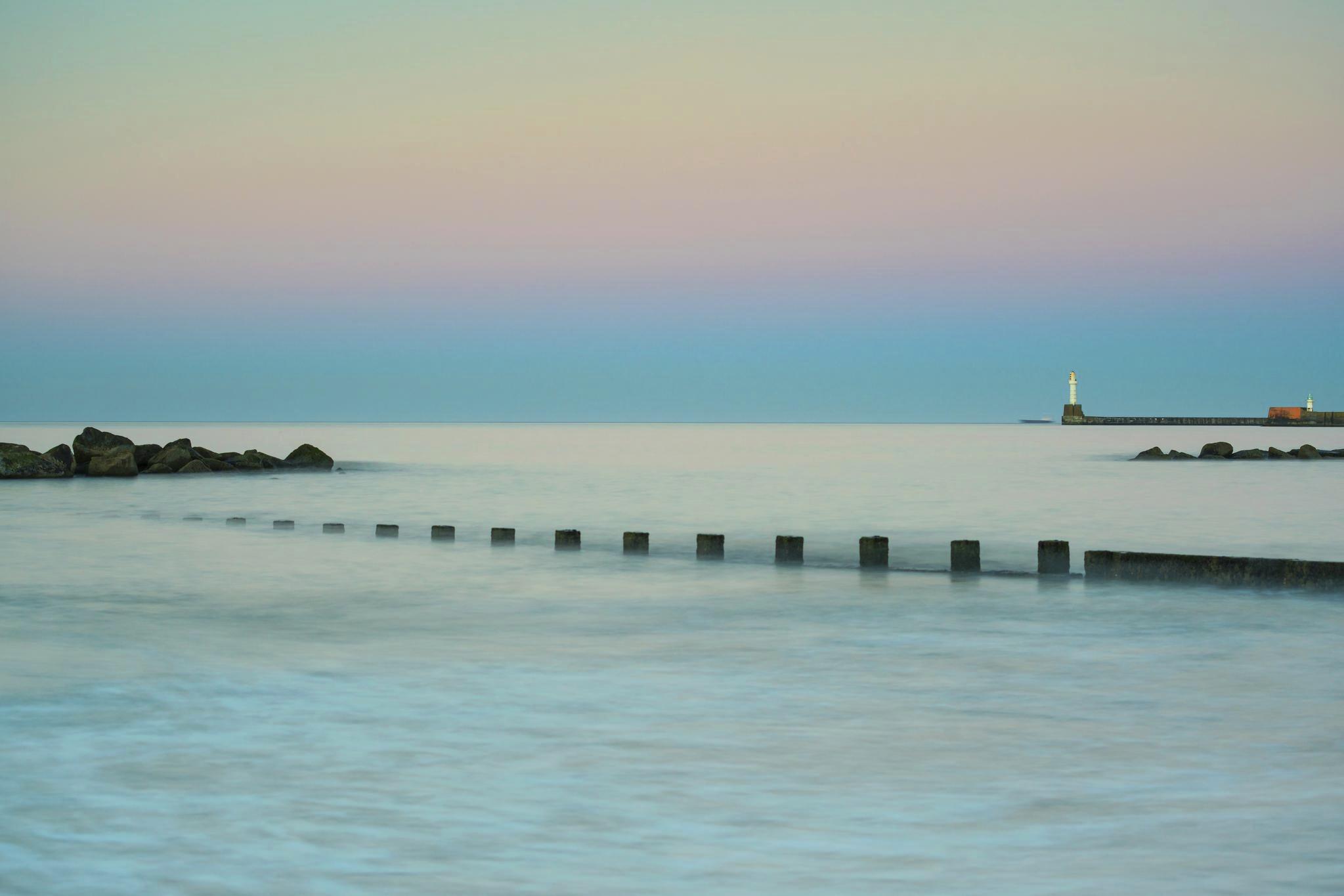 A tranquil coastal beach with a lighthouse in the distance