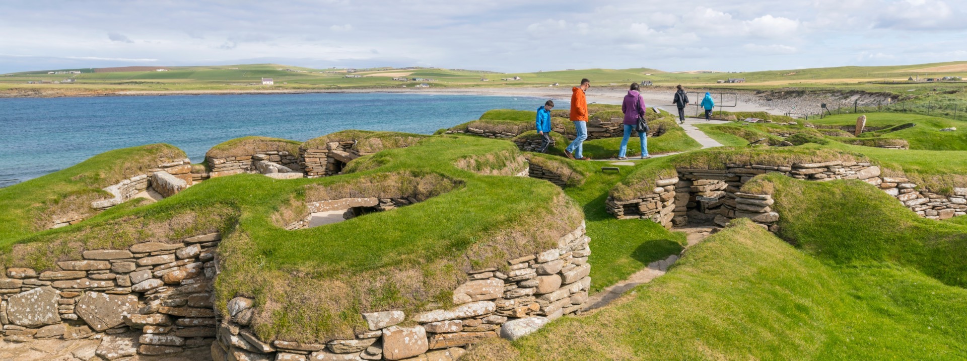 I visitatori esplorano Skara Brae, parte del sito neolitico delle Orcadi, patrimonio dell'umanità, presso la baia di Skail