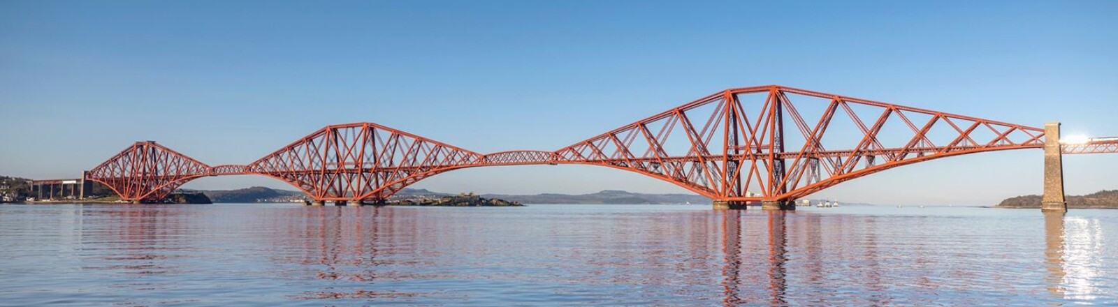 The red Forth Bridge over the Firth of Forth against a blue sky