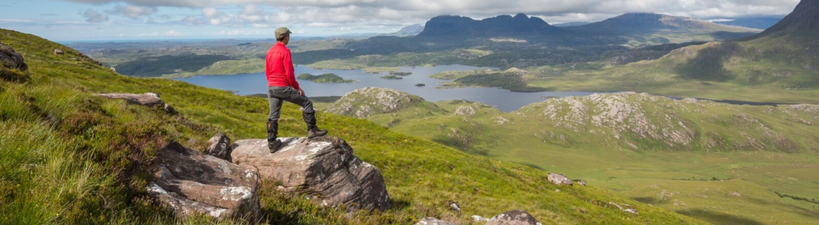 Hillwalker taking in the views over to Suilven from Stac Pollaidh, a mountain in the north-west Scottish Highlands