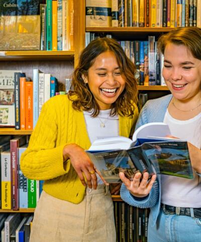 Zwei junge Frauen stöbern bei Topping & Company Booksellers in Edinburgh durch die Bücherregale.