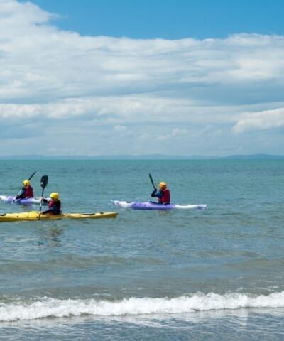 Quattro kayak in mare, vicino alla spiaggia in una giornata di sole