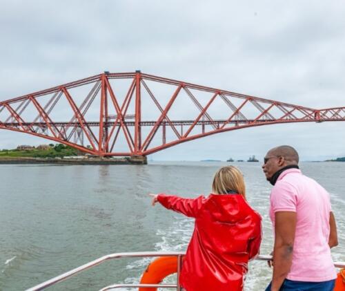 Ein Paar sieht bei einer Bootstour mit der Maid of the Forth die Forth Bridge.
