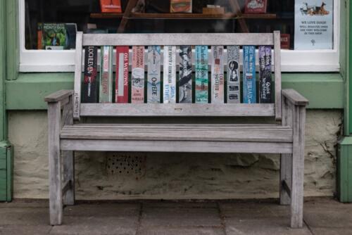 A bench with book spines as the back panel, sitting outside a bookshop