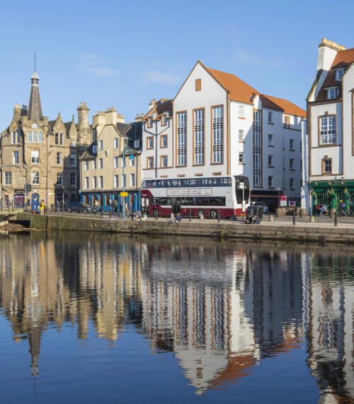 The buildings sitting beside the river, a bus going past at the Shore in Leith
