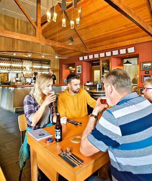Un gruppo di persone sedute a un tavolo per un drink e un pasto all'interno della Orkney Brewery