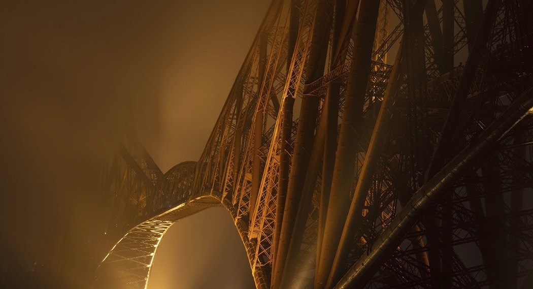 Nahaufnahme der Forth Bridge bei Nacht im Nebel.