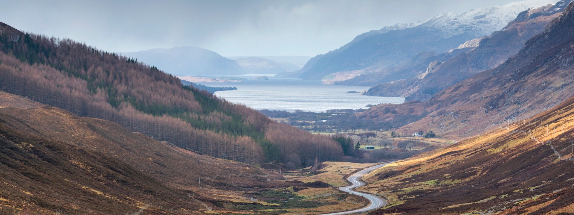 The road cuts through the hills and mountains to the loch in the distance